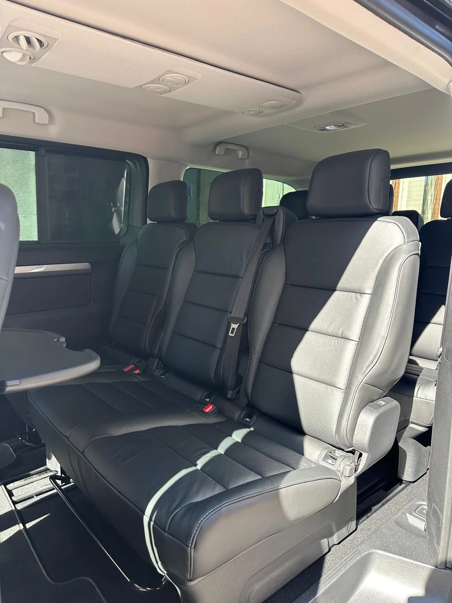 Side view of leather passenger seats and folding table inside the Movira Transfers VIP van