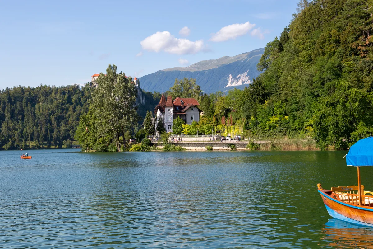 Boat on Lake Bled surrounded by forest and Alpine mountains