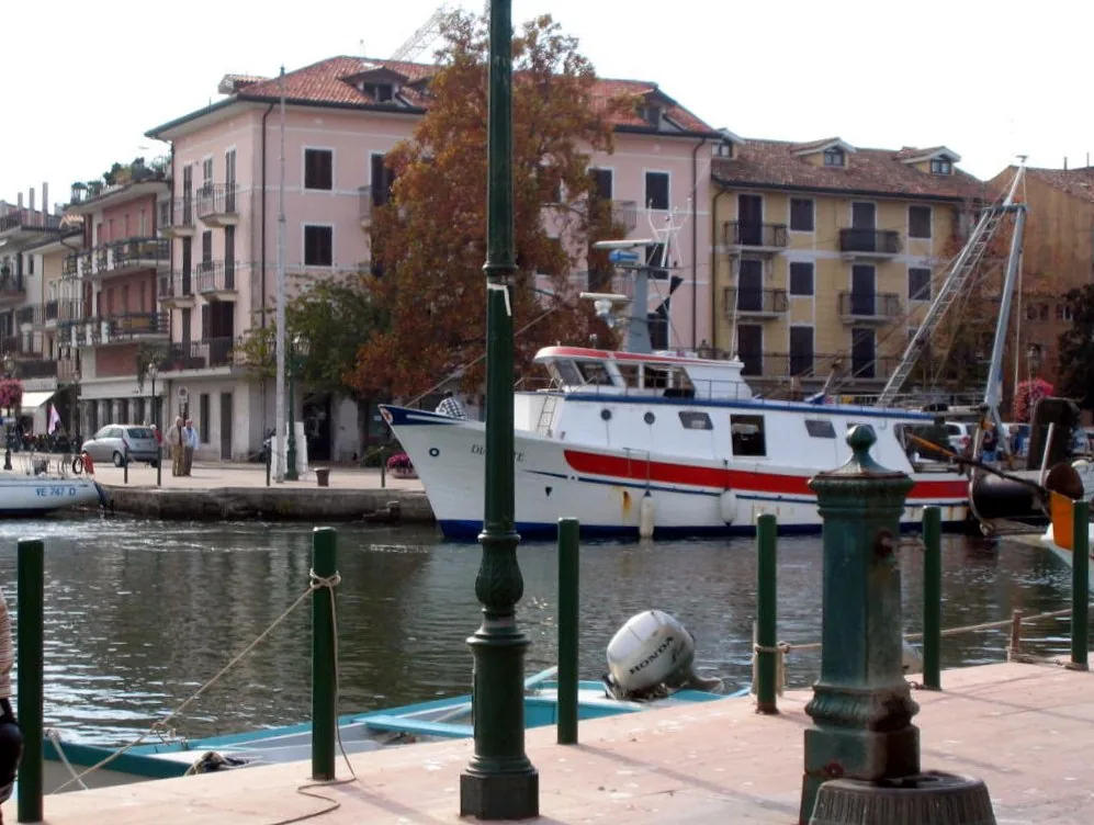 Boats in Grado harbour beside waterfront buildings